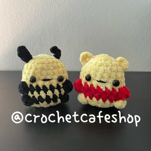 May include: Two crocheted plush toys, one black and yellow with a checkered pattern and the other yellow with a red scarf. The toys are sitting on a dark wooden surface. @crochetcafeshop