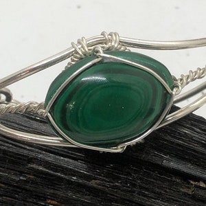 May include: A silver wire wrapped bracelet with a green malachite stone.