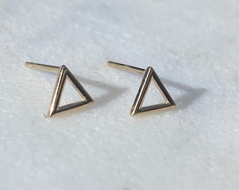 Puede incluir: Un par de pendientes de triángulo de oro. Los pendientes son simples y minimalistas, con un diseño de triángulo hueco.