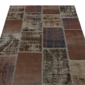 May include: A rectangular patchwork rug with a distressed, vintage appearance. The rug features a variety of brown, beige, and muted blue-gray rectangular patches. The patches have varying textures and shades, creating a unique, aged aesthetic. The rug is suitable for home decor.