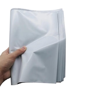 May include: A stack of white, folded, poly mailer shipping envelopes. The envelopes are held in a hand, with the edges of the envelopes visible. The envelopes are made of a shiny, waterproof material.