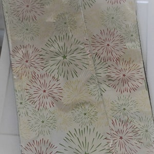 Puede incluir: Dos rollos de papel de regalo blanco con un patr&oacute;n de fuegos artificiales rojo, verde y amarillo.