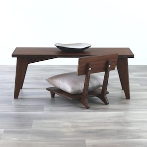 May include: A dark brown wooden coffee table with a white ceramic bowl on top. A small wooden chair with a gray cushion is in front of the table.