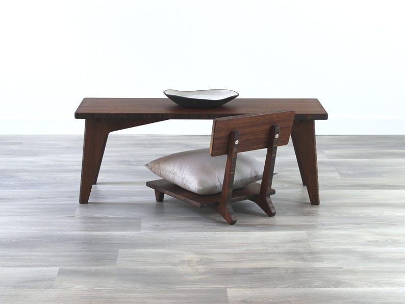 May include: A dark brown wooden coffee table with a white ceramic bowl on top. A small wooden chair with a gray cushion is in front of the table.