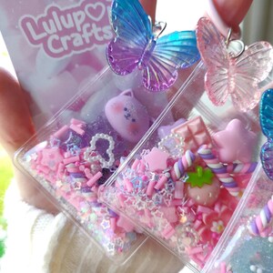 May include: Clear rectangular resin keychains filled with pink and purple confetti, stars, and small charms. Each keychain features a colorful butterfly on top. The keychains are decorated with a variety of cute, colorful charms and the text "Lulup Crafts".