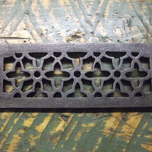 May include: A rectangular cast iron vent cover with a decorative floral pattern. The vent cover is dark gray and has a slightly distressed finish.