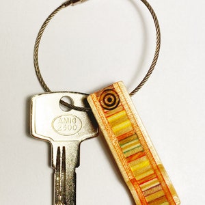 Handmade keychains made from recycled skateboard decks, a thin layer of clear resin, and finished with a steel hook.