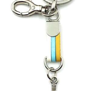 May include: A silver key chain with a blue and yellow striped leather strap and a silver paddle shaped charm.