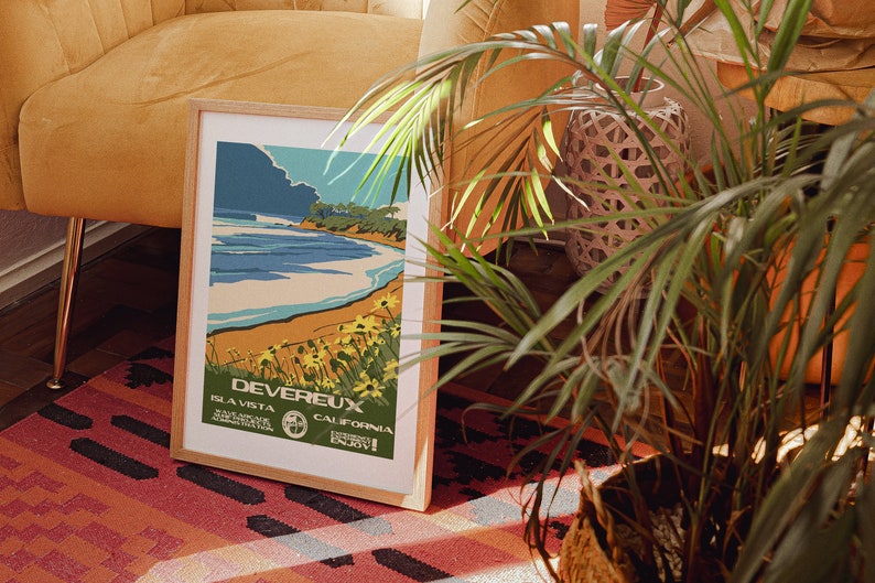 May include: A framed vintage travel poster with a blue, green, and yellow color scheme. The poster features a beach scene with a blue ocean, a sandy beach, and a green hillside. The text on the poster reads "Devereux, Isla Vista, California, Enjoy!"
