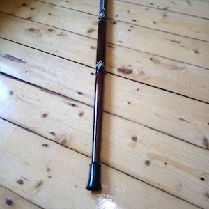 May include: A wooden walking stick with a carved handle and a black rubber tip.