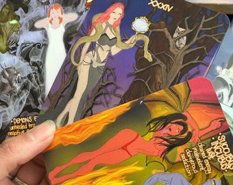 Può includere: Un mazzo di tarocchi "The Mystic Quest", con una carta tenuta in mano raffigurante un succube e un incubo in fiamme. Altre carte con illustrazioni e testo sono sparse.