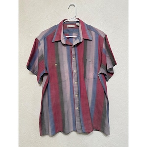 May include: Short-sleeved button-down shirt with vertical stripes in red, blue, gray, and white. The shirt has a collared neckline, a chest pocket, and is hanging on a white hanger. The brand name is visible on the collar.