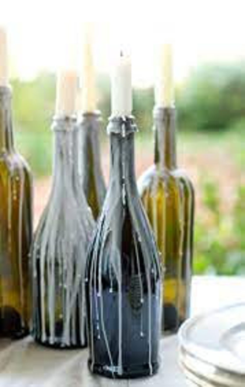 May include: Four glass wine bottles with white candles inside, the wax has dripped down the sides of the bottles, creating a rustic and elegant look.