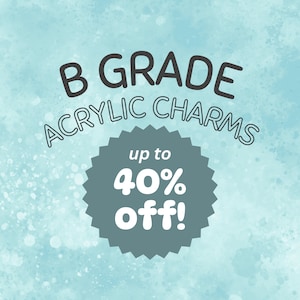 May include: A blue watercolour background with white splatter paint. The text "B GRADE ACRYLIC CHARMS" is in black. A grey starburst shape with the text "up to 40% off!" in white.