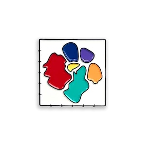 May include: A square enamel pin featuring a white background enclosed by a thin black metal frame. The center displays an abstract arrangement of six smooth, glossy, organic-shaped color patches in red, dark blue, purple, orange, teal, and yellow.