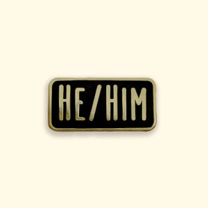 He/Him pronoun black and gold enamel pin badge on yellow background