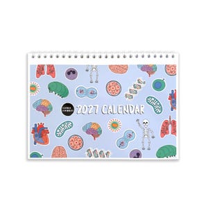 May include: A 2027 spiral-bound wall calendar with a light blue background featuring a repeating pattern of colorful science-themed illustrations including brains, hearts, lungs, skeletons, DNA strands, and cells, with the text Science Scribbles 2027 Calendar.