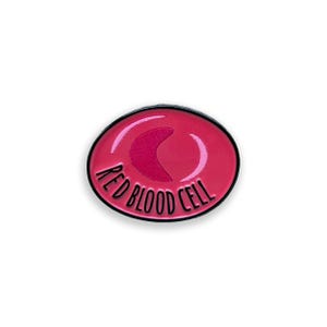 May include: A red blood cell enamel pin with a black border. The pin features a stylized illustration of a red blood cell with the words "RED BLOOD CELL" in white lettering around the edge of the pin.
