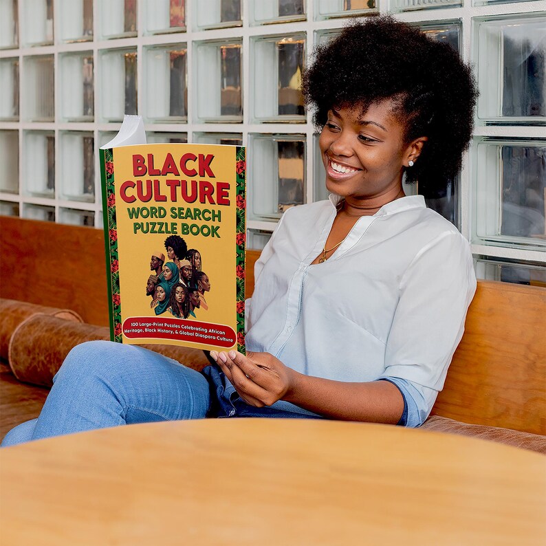 K&ouml;nnte beinhalten: Eine Person h&auml;lt ein Buch mit dem Titel "BLACK CULTURE WORD SEARCH PUZZLE BOOK". Das Buch hat einen gelben Einband mit roten und gr&uuml;nen Akzenten und zeigt Illustrationen verschiedener Gesichter. Der Untertitel des Buches lautet "100 Gro&szlig;druck-R&auml;tsel zur Feier des afrikanischen Erbes, schwarzer Schriftsteller und der globalen Diaspora-Kultur."
