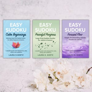 Op de afbeelding: Drie sudoku-puzzelboeken met de titels "Calm Beginnings", "Peaceful Progress" en "Focused Flow". Elk boek heeft een uniek kleurenschema en ontwerp, met tekst en bloemmotieven. De auteur is Laura D. Goetz.