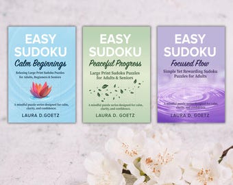 May include: Three sudoku puzzle books with titles "Calm Beginnings", "Peaceful Progress", and "Focused Flow". Each book features a different color scheme and design, with text and floral elements. The author's name is Laura D. Goetz.
