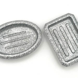 May include: Two silver soap dishes, one oval and one rectangular, with a textured, sparkly finish.