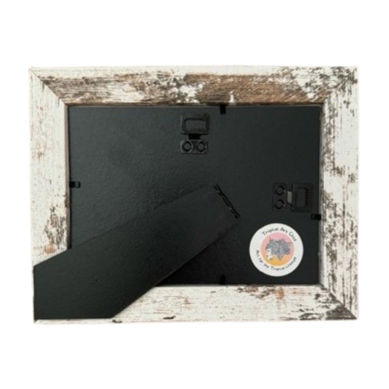 Puede incluir: Marco de fotos de madera blanca con un paspart&uacute; negro y una peque&ntilde;a pegatina en la esquina inferior derecha que dice "Tropics Art Co."