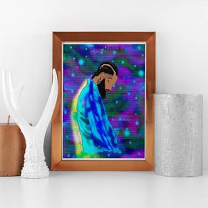 May include: Framed art print featuring a stylized illustration of a person with a beard, wearing a blue jacket, set against a vibrant, colorful background. The text "Nipsey Hussle" is at the top. The artwork is displayed on a white surface.