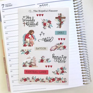 May include: A sheet of stickers with religious themes, including images of Jesus, a lamb, crosses, and floral arrangements. Text includes "The Hopeful Planner," "By His Wounds We Are Healed," and "Beauty From Ashes."
