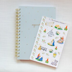 May include: A sheet of Christmas-themed stickers featuring illustrations of the Nativity scene, candles, holly, and the text "The Story of Christmas is a Story of Love", "Oh Holy Night", and "Joy to the World".