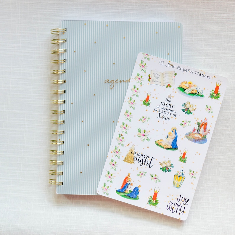 May include: A sheet of Christmas-themed stickers featuring illustrations of the Nativity scene, candles, holly, and the text "The Story of Christmas is a Story of Love", "Oh Holy Night", and "Joy to the World".