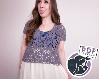 Pode incluir: Uma mulher vestindo um top de crochê cinza com um design floral. O top tem um decote em V e mangas curtas. A mulher está vestindo uma saia branca e tem cabelo castanho longo. A imagem também inclui um sinal que diz "PDF PATTERN" com um corvo de desenho animado segurando-o.