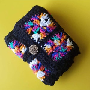May include: Black crocheted pouch with colorful floral designs and a gold button closure.
