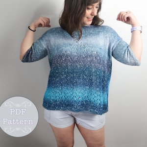 Puede incluir: Un suéter de punto azul y blanco degradado con un corte holgado y mangas 3/4. El suéter está hecho con un hilo texturizado y tiene un brillo sutil.