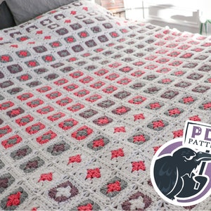 Op de afbeelding: Een gehaakt deken met een witte achtergrond en een herhalend patroon van roze en grijze vierkanten. Het deken ligt op een bed met een grijs hoofdeinde. Een bord in de rechterbenedenhoek zegt "PDF PATTERN".