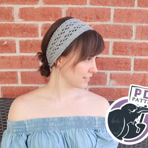 May include: A woman wearing a gray crocheted headband with a lacy pattern. The headband is worn over her hair, which is pulled back in a bun. She is wearing a light blue off-the-shoulder top. The background is a brick wall. A black and white illustration of a crow holding a sign that says "PDF PATTERN" is in the lower right corner of the image.