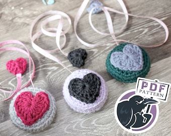 May include: Three crocheted heart-shaped measuring tape holders in pink, purple, and green. Each holder has a crocheted heart in a different color. The text "PDF PATTERN" is visible in the image.