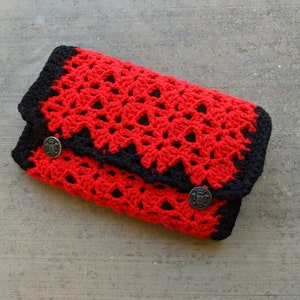 May include: A red and black crocheted clutch with two decorative buttons.