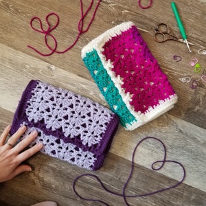 May include: Two crocheted blankets, one purple and one pink with white and teal accents, are laid out on a wooden surface.  A heart shape is formed with purple yarn.