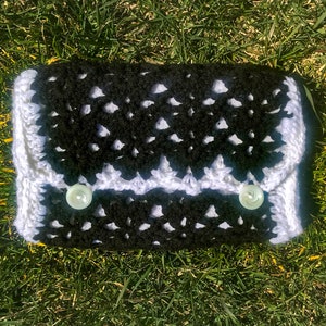May include: A black and white crocheted clutch with two white buttons.