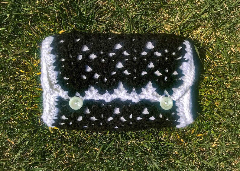 May include: A black and white crocheted clutch with two white buttons.