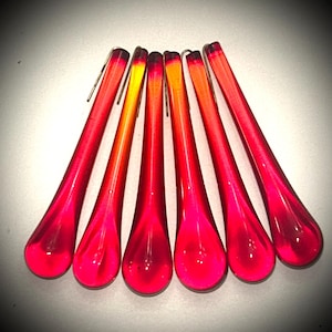 May include: Six elongated, teardrop-shaped glass chandelier crystals arranged in a fan pattern. Each piece features a vibrant gradient transitioning from a deep red at the base to a bright orange-yellow at the top, with a small metal hook attached.