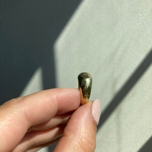 May include: A gold signet ring with a small, round, pink gemstone set in the center.