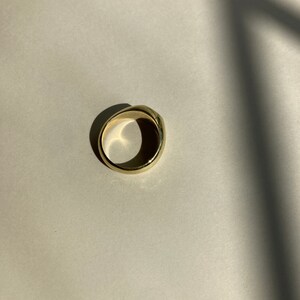 May include: A gold ring with a smooth, rounded surface.