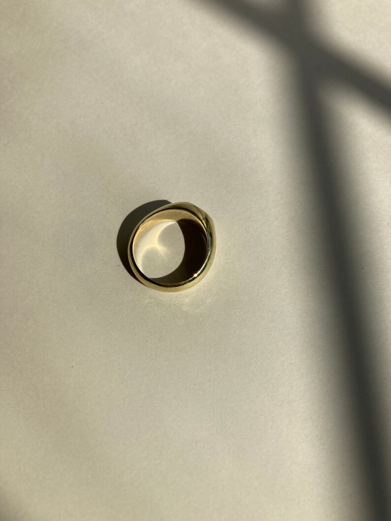 May include: A gold ring with a smooth, rounded surface.