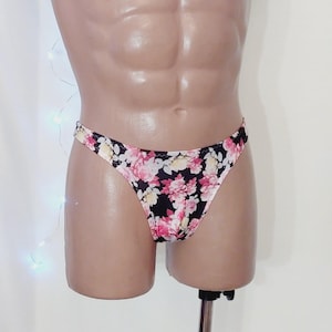 Könnte beinhalten: Schwarze Satin-Unterwäsche mit einem Blumendruck mit rosa, weißen und gelben Blumen.