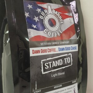 May include: A black coffee bag with a red, white and blue American flag design. The bag features the text "Gun Barrel Coffee", "Veteran Owned Company", "Damn Good Coffee... Damn Good Cause", "Stand To", "Light Blend", and "Net Weight 12oz (340g)".