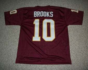 May include: Burgundy football jersey with white and gold lettering. The jersey has the number "10" and the name "BROOKS" on the back.