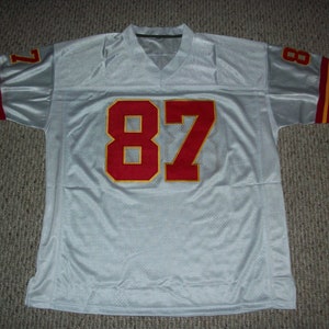 May include: White football jersey with red and gold trim. The number 87 is printed on the front in red with a gold outline.
