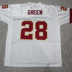 May include: White football jersey with burgundy and gold trim. The number 28 is on the back with the name "GREEN" above it.